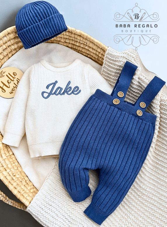 Custom baby name Newborn Knit Set featuring a cozy sweater, suspender pants, and beanie in a basket.