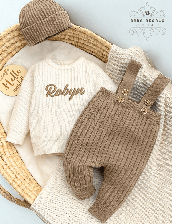 Custom baby name Newborn Knit Set featuring a cozy sweater, suspender pants, and beanie in a basket.