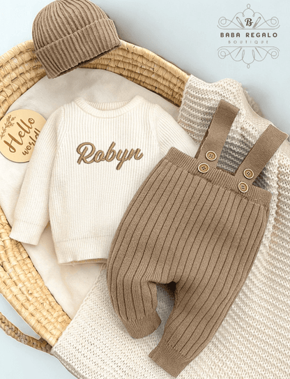 Custom baby name Newborn Knit Set featuring a cozy sweater, suspender pants, and beanie in a basket.