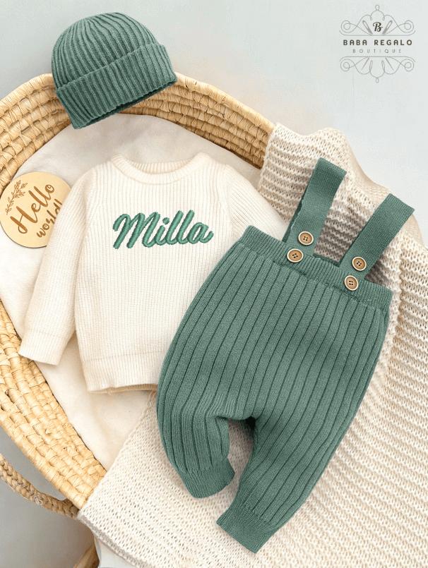 Custom baby name Newborn Knit Set featuring a cozy sweater, suspender pants, and beanie in a basket.